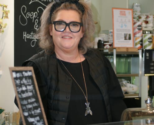 Nancy Bakker met een glimlach achter de balie Bij Moeders in de Kosterij
